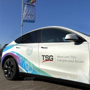 Elektroauto mit TSG-Logo auf Firmenparkplatz.