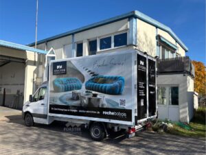 Transporter mit Wohnmöbelwerbung vor einem Gebäude